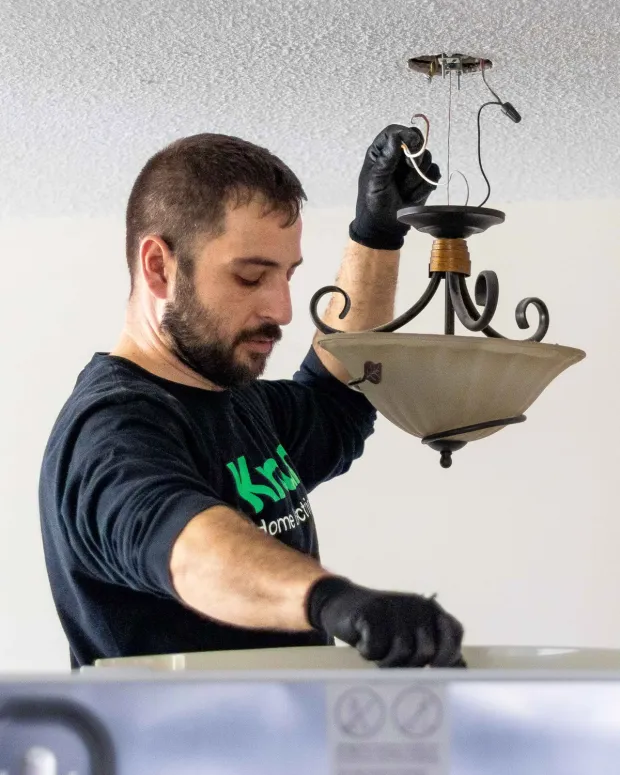 Electrician installing light fixture